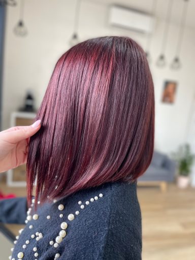 Cabello lacio y brillante en un corte bob, color rojo intenso con un fondo moderno.